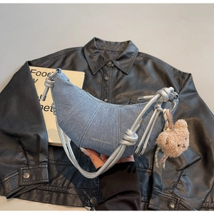 Detail der hellblauen Denim-Halbmondtasche mit silbernem Seilriemen und Bärenanhänger