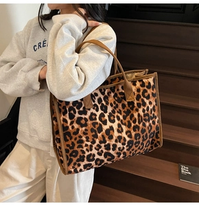 Detail of leopard print tote bag featuring sturdy brown reinforced straps and canvas texture