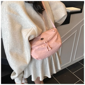 Detail shot of a pink waterproof nylon crossbody bag worn over a grey sweatshirt