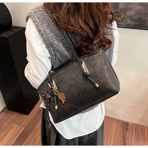 Dettaglio borsa tote vintage in pelle nera con nodo e ciondoli in metallo da tennis