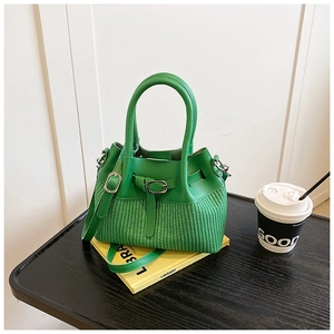 Detail of green leather and woven bucket bag showing metal buckle and texture