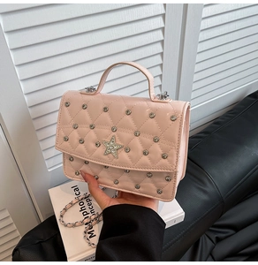 Close-up of pink quilted crossbody bag with star emblem and metal chain strap details