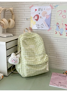 Detailed view of green checkered backpack with lace trim and plush bunny charm accessory