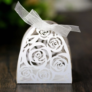 Macro detail of laser-cut rose patterns on elegant white wedding gift box with ribbon