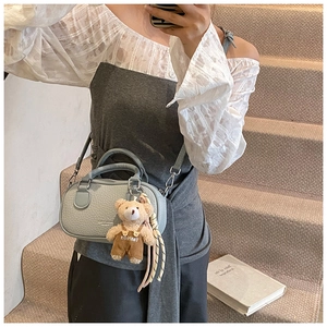 Detail of blue pebbled leather bowling bag with cute teddy bear charm on shoulder strap