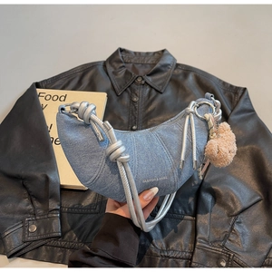 Detail der hellblauen Denim-Halbmondtasche mit silbernem Seilgriff und Bärenanhänger