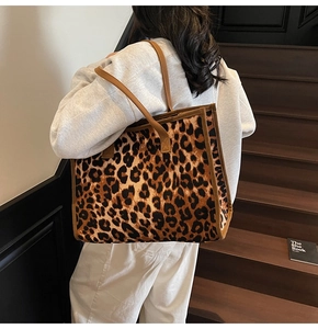 Close-up of leopard print tote bag with brown straps styled on model in a cozy setting
