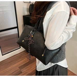 Dettaglio della borsa tote in pelle nera opaca con nappa intrecciata e metallo oro