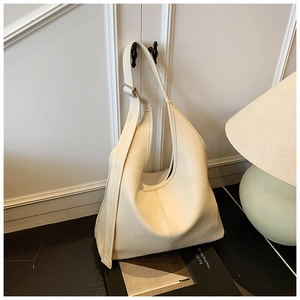 Close-up of cream-colored hobo bag with adjustable wide strap and silver metal buckle