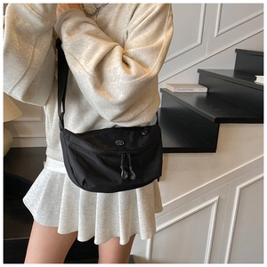 Detail of adjustable strap and circular logo on black nylon crossbody dumpling bag