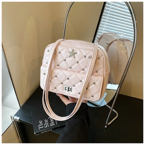 Detail of pink quilted tote bag with silver star emblem and glossy finish on desk