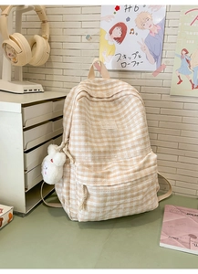 Detailed close-up of plaid backpack featuring lace trim and a cute plush rabbit pendant