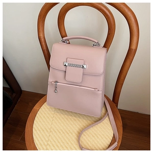 Detail der rosa Lederhandtasche mit Metallkettenakzent und Glockenanhänger an der Tasche
