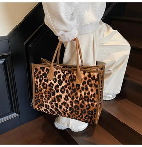 Leopard print tote bag with brown straps styled on shoulder in a minimalist indoor setting