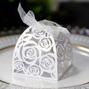 Close-up of white laser-cut rose hollow favor box with elegant silver organza ribbon