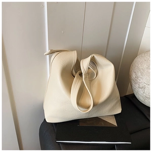 Close-up of cream textured faux leather bucket bag with elegant pleated details