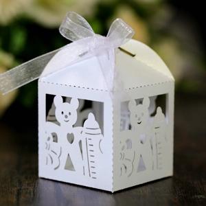 Close-up of laser-cut white baby shower candy box with bear and bottle motifs