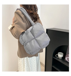 Detailaufnahme der hellgrau gesteppten Puffer-Schultertasche mit breitem Gurt an einem Model