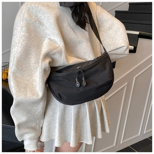 Close-up of black nylon half-moon crossbody bag with dual zipper and adjustable strap