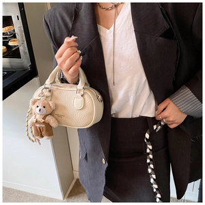 Detail of cream bowling bag in lychee pattern leather with a cute plush bear pendant