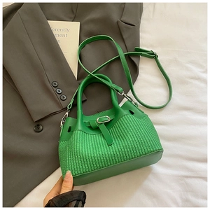 Detail of green woven bucket bag with leather buckle and adjustable strap