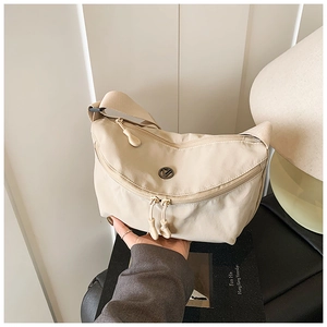 Detail of beige nylon crescent crossbody bag with adjustable strap and dual zipper closure