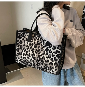 Black and white leopard print tote bag shown on shoulder for size reference