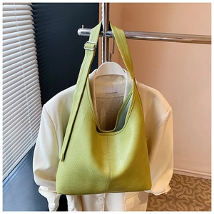 Detail showing the lychee leather texture and silver hardware of the green tote bag