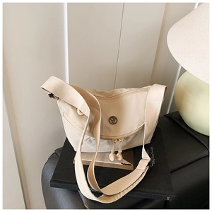 Detail of beige crescent crossbody bag featuring metal V logo and adjustable wide strap