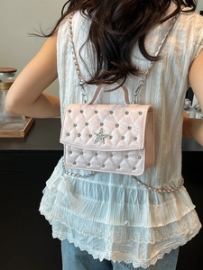 Pink quilted mini square bag with sequin finish and star charm shown in a crossbody style