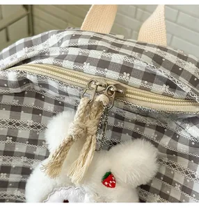 Detail of smooth metal double zippers with gray plaid fabric and strawberry plush charm