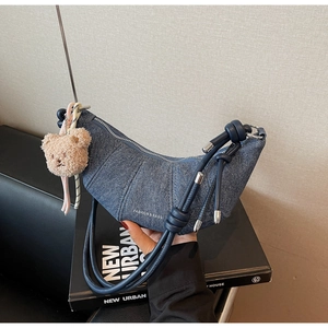 Detail einer blauen Denim-Hörnchen-Tasche mit Teddybär-Anhänger und Logo