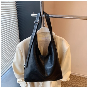 Detail of black large tote bag with lychee texture faux leather and silver buckle strap