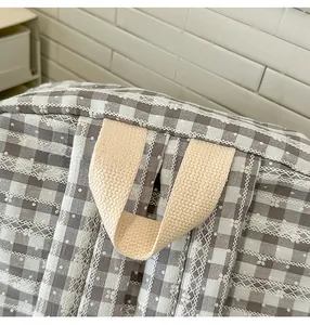 Detail of grid pattern fabric with lace embroidery and canvas carry handle on the backpack