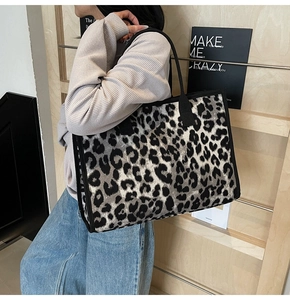 Detail of trendy leopard print tote bag with black canvas straps on model shoulder