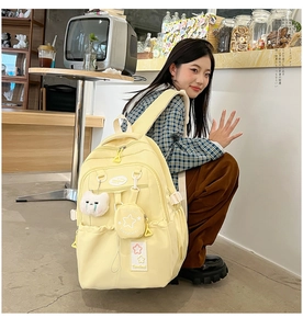 Detailed view of yellow waterproof backpack with plush bear and mini star pouch