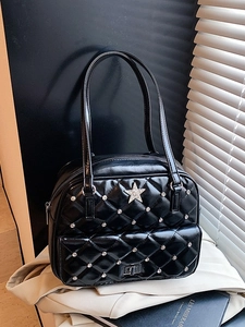 Quilted black tote bag with silver star and studs shown under artistic window light