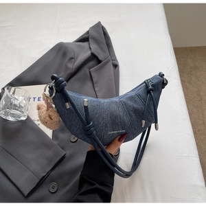 Detail der Jeans-Halbmondtasche mit Knotengurt und kleinem Bären-Plüsch-Anhänger