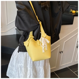 Detail of yellow lychee texture bucket bag with white lace bow and pearl pendant
