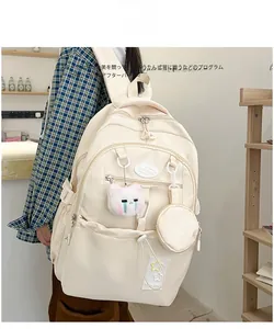Detail view of cream white large capacity backpack with pockets and cute cat pendant