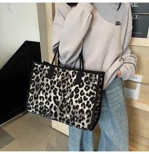 Detail of trendy leopard print tote bag with black fabric handles and woven trim