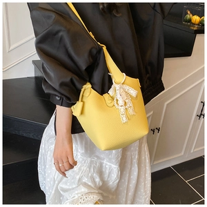 Close-up of bright yellow bucket bag with lychee texture and pearl lace bow charm