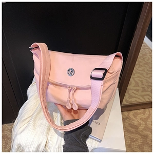 Detail view of pink nylon crescent bag featuring dual zippers and adjustable shoulder strap