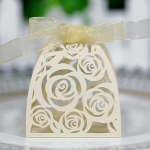 Detail of laser-cut rose hollow favor box with gold ribbon on elegant cream pearlescent paper