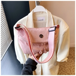 Detailed shot of pink casual crossbody bag showing fabric texture and metal logo