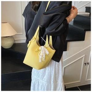 Detail of yellow bucket bag featuring lychee grain leather and lace bow charm