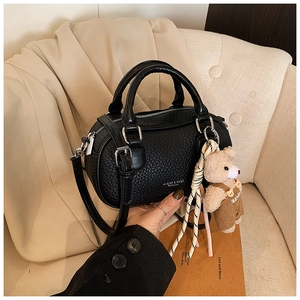 Detail of black lychee grain leather bowling bag with silver zippers and bear charm