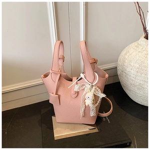 Detail of pink lychee leather bucket bag with pearl lace charm and long shoulder strap