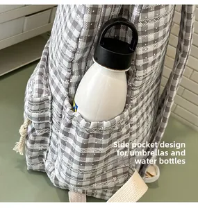 Detail of grey gingham backpack side pocket with lace trim holding a water bottle