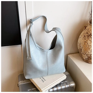 Detail of light blue hobo bag with pebble leather texture on a metal suitcase